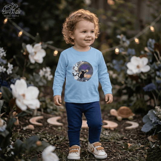 Toddler wearing a Celestial Cat toddler cat long sleeve shirt, surrounded by flowers, showcasing a whimsical moonlit design.