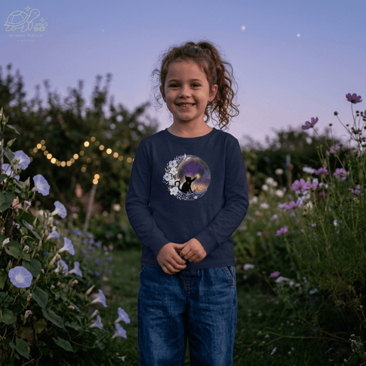 Celestial Cat Kids Long-Sleeve Tee worn by a smiling child in a garden at dusk with flowers.