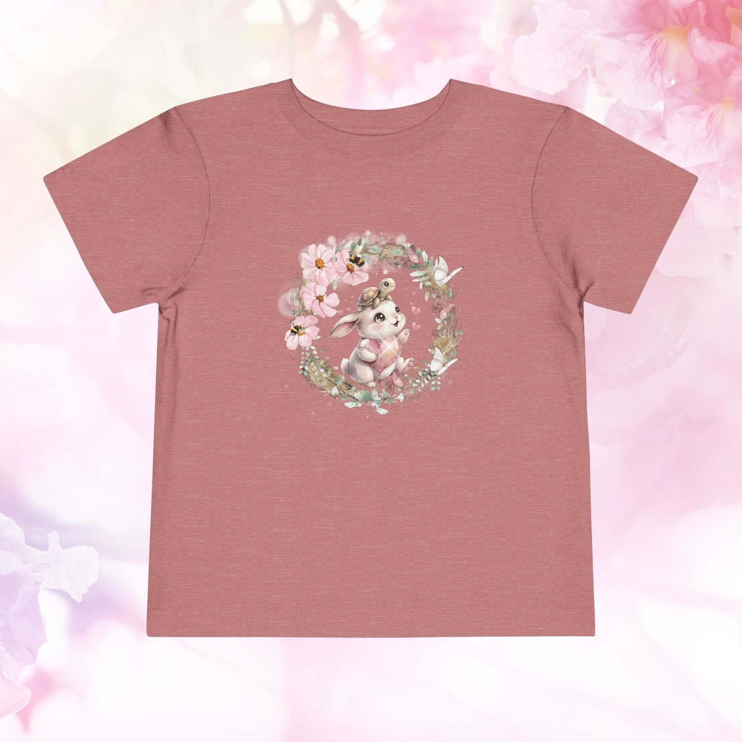 Toddler bunny t-shirt featuring a watercolor bunny surrounded by spring flowers on a rose-colored background.