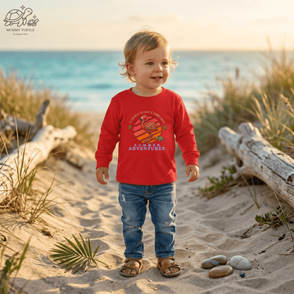 Toddler wearing a red Summer Adventure toddler flamingo long sleeve shirt on a beach.