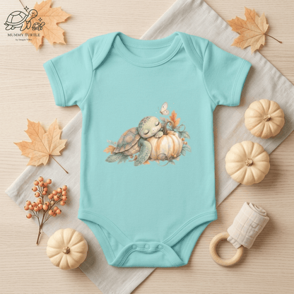 Aqua Harvest Friends Infant Bodysuit styled in a warm fall flat lay featuring the turtle and turkey harvest friendship artwork.