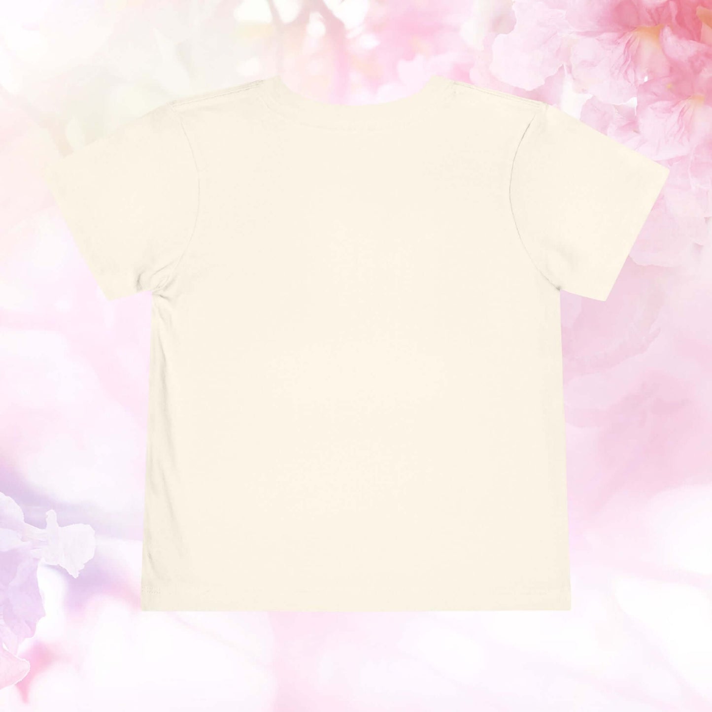 Back view of a beige toddler bunny t-shirt on a pastel floral background.