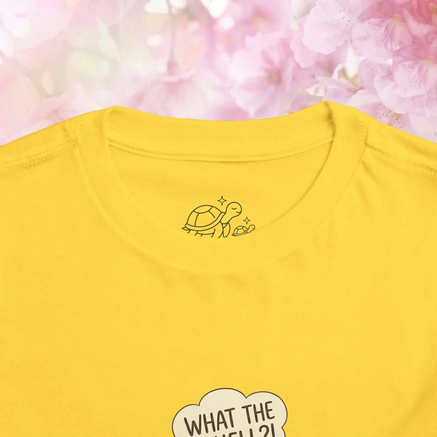 What the Shell?! toddler turtle t-shirt featuring a playful turtle graphic on a yellow background.